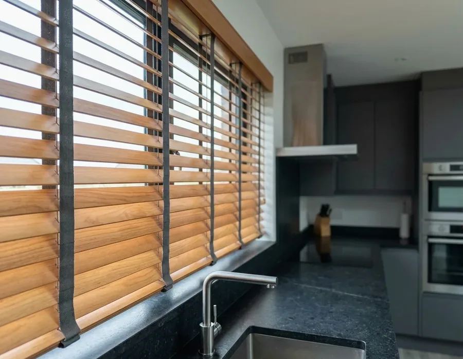 Timber venetian blind with horizontal wooden slats tilted open above a kitchen counter in a Lonehill home